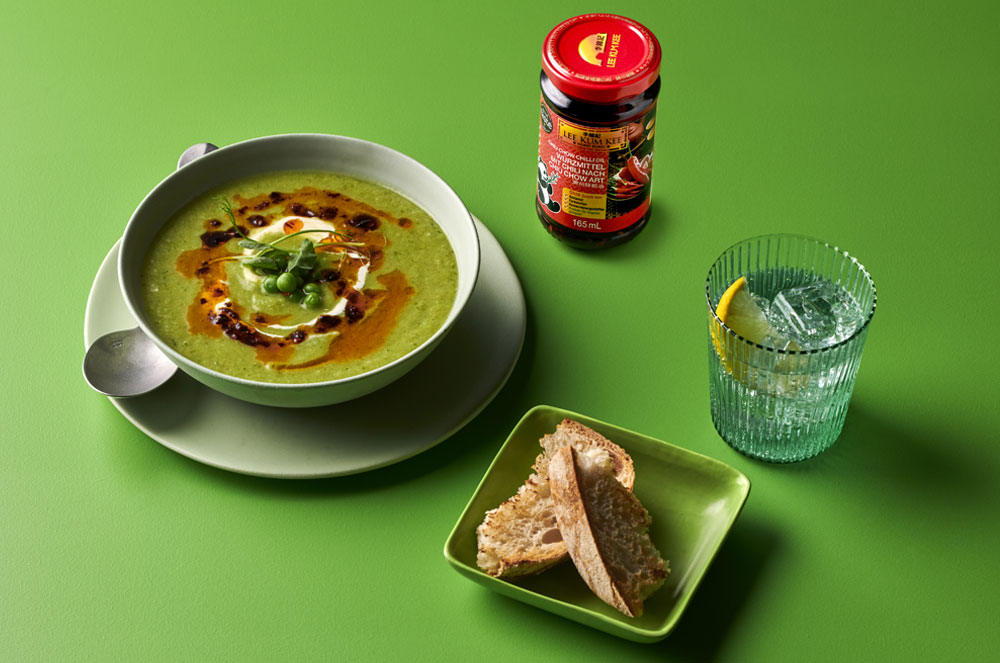 Erbsensuppe in Schale mit Brot, Wasser und Chiu Chow Chilli Öl daneben